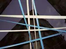 Blue and white beams cross above a dark building facade.