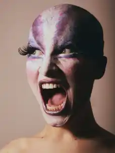 Alisha Hellmuth screaming, wearing a bald cap and purple and white face paint, at the Otto-Falckenberg-Schule