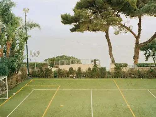 A small football pitch beneath tall trees in Napoli.