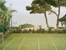 A small football pitch beneath tall trees in Napoli.