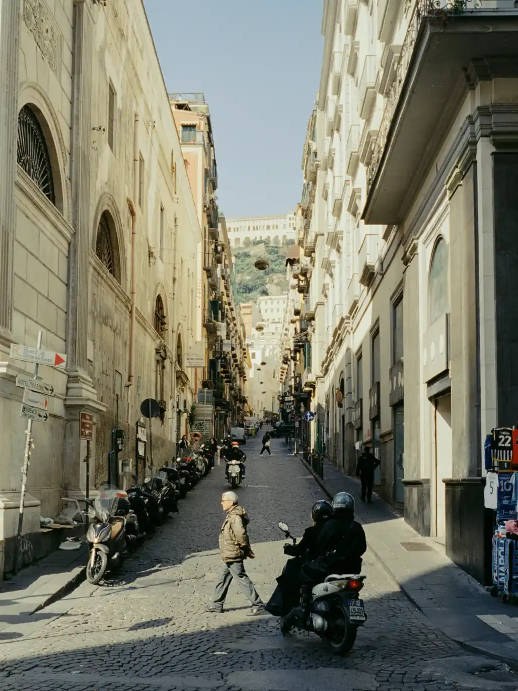 A narrow, sunlit street lined with tall buildings in Napoli.