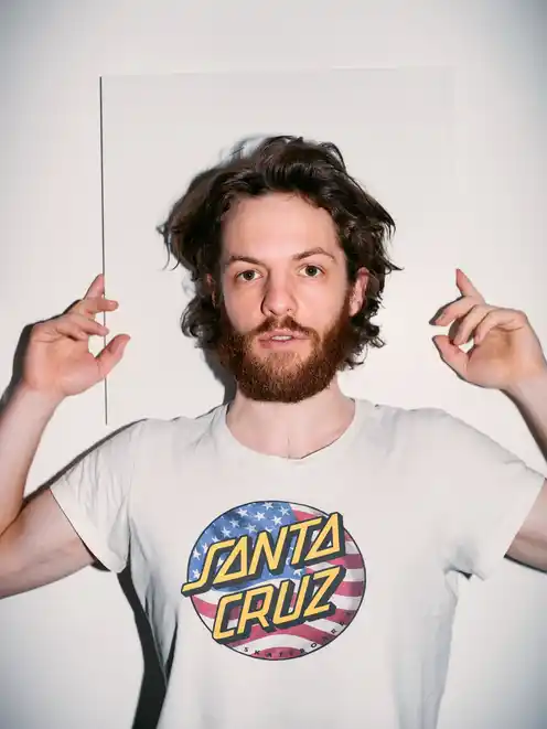 Portrait of Marlon Bienert in front of a white wall holding his hands up