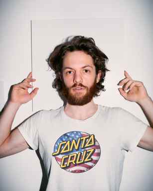 Portrait of Marlon Bienert in front of a white wall holding his hands up
