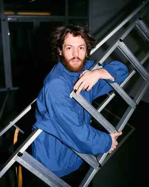 Portrait of Marlon Bienert with a blue jacket holding a ladder