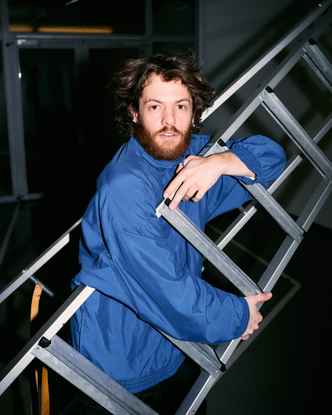 Portrait of Marlon Bienert with a blue jacket holding a ladder