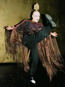 Martin Weigel in a feathered costume and sparkling cape backstage at Auerbach