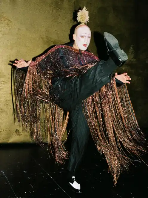 Martin Weigel in a feathered costume and sparkling cape backstage at Auerbach