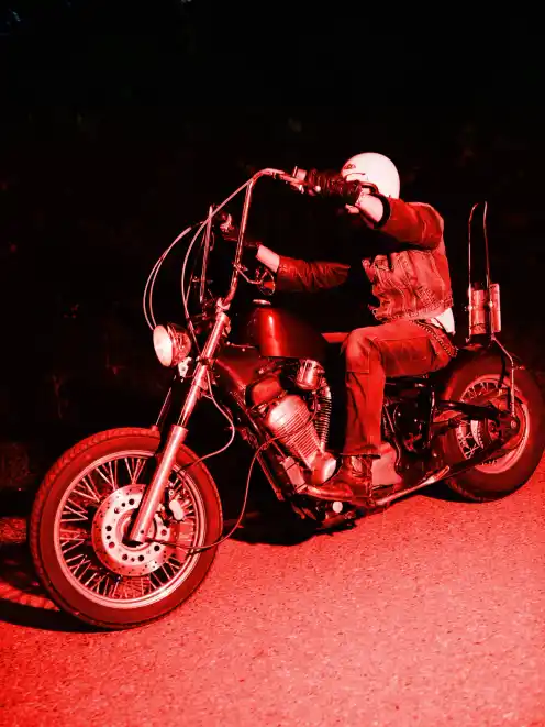 A side profile of a man riding a motorbike shot with a red flash from the project Elsewhere