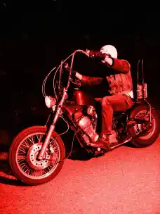 A side profile of a man riding a motorbike shot with a red flash from the project Elsewhere
